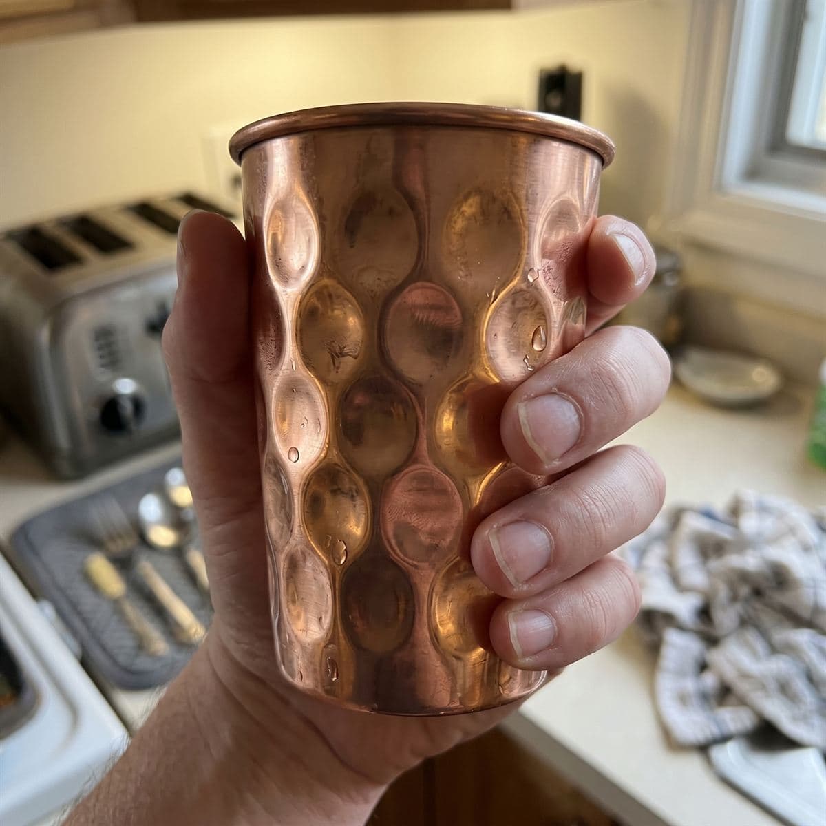 Close-up of a hand around a hammered copper tumbler